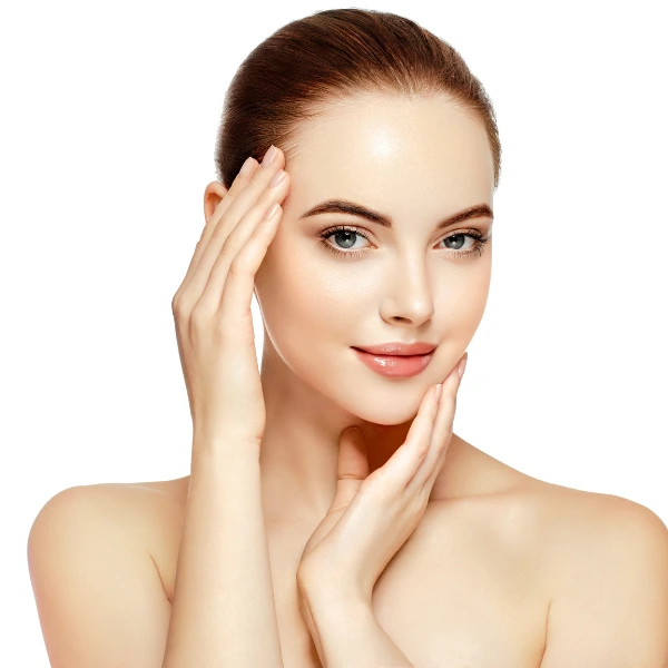 A woman with clear skin and light makeup touches her face with both hands, posing against a white background, embodying the benefits of antioxidant therapy in Nepal.